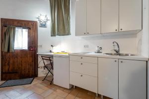 una cucina con armadi bianchi e lavandino di Urbino Historical Central Studio! a Urbino