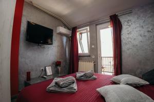 - une chambre avec un lit rouge et des serviettes dans l'établissement Bordeaux City Center, à Novi Sad