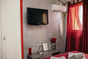 ノヴィサドにあるBordeaux City Centerの赤いカーテン付きの壁にテレビが備わる部屋