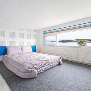 a bedroom with a large bed with a large window at Jeju Turning point Pension in Seogwipo