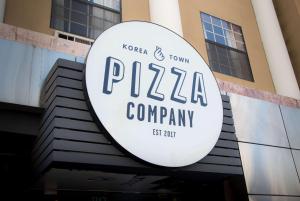 a sign for a pizza company in front of a building at Ramada by Wyndham Los Angeles/Wilshire Center in Los Angeles