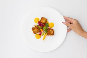 a person holding a white plate with food on it at La Darsena Boutique Hotel & Restaurant in Tremezzo