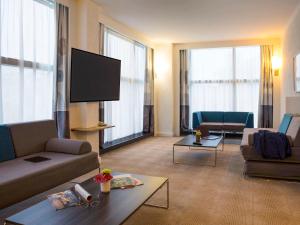 a living room with couches and a flat screen tv at Novotel Genève Centre in Geneva