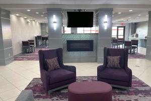 um átrio com 2 cadeiras e uma televisão de ecrã plano em La Quinta Inn & Suites by Wyndham Tulsa Midtown em Tulsa