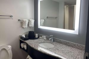 a bathroom with a sink and a mirror and a toilet at La Quinta Inn & Suites by Wyndham Tulsa Midtown in Tulsa