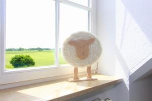 un jouet de mouton farci assis sur un rebord de fenêtre dans l'établissement Haus Jenny Wohnung H 5a, à Redewisch