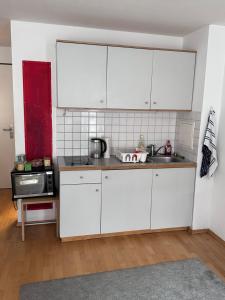 a kitchen with white cabinets and a sink at Lovely Big Studio for two in Munich