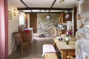 cocina con mesa y pared de piedra en Rose Cottage, en Bude