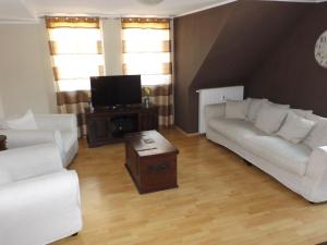 een woonkamer met twee witte banken en een tv bij Deutsches Haus in Willingen