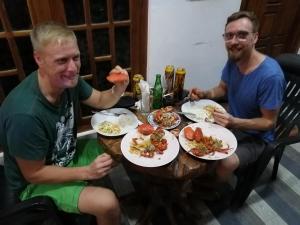亭可马里beach life hostal的两个坐在餐桌上吃盘子的人