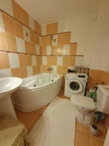 a bathroom with a tub and a toilet and a washing machine at Suceava apartment in Suceava