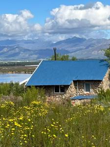 a blue roof on a stone building with a field of flowers at Welbedacht Game & Nature Reserve in Tulbagh