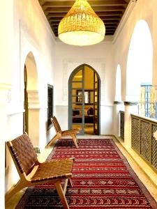 a hallway with two benches on a rug and a chandelier at Riad Hadika Maria in Marrakesh
