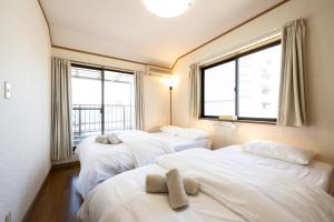 three beds in a room with three windows at VILLA MorE in Tokyo