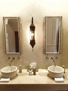 a bathroom with two sinks and two mirrors at Riad Hadika Maria in Marrakesh