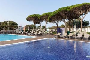 a swimming pool with chaise lounges and chairs at Alua Illa de Menorca in S'Algar