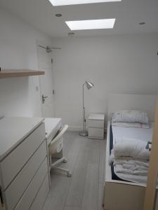 um quarto branco com uma cama, uma secretária e um lavatório. em The Old Guest House, 249A Norbury Avenue em Norbury