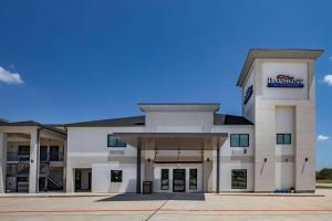 un gran edificio blanco con un cartel. en Baymont by Wyndham Freeport Texas, en Freeport