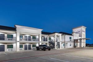 a large white building with a truck parked in front at Baymont by Wyndham Freeport Texas in Freeport