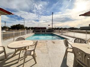 a patio with tables and chairs and a swimming pool at Motel 6 Abbeville, AL in Abbeville