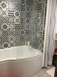 a bathroom with a tub and a tile wall at Appartement très lumineux in Égat