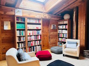 uma sala de estar com duas cadeiras e prateleiras cheias de livros em Chalet Ciamarella em Lanslevillard