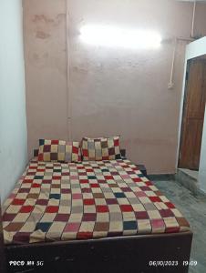 a bedroom with a bed with a checkered blanket at NAVRANG DELHI BACKPACKER in New Delhi