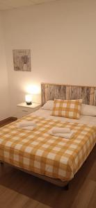 1 cama con 2 almohadas y manta a cuadros en Apartamentos Costa de la Luz Béjar 28-30, en Huelva