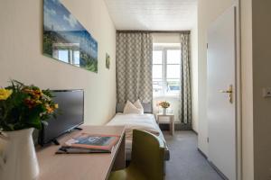 a hotel room with a bed and a desk with a table at Hotel-Pension am Siegestor in Munich