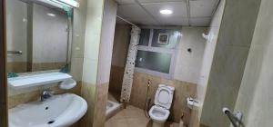uma casa de banho com um lavatório, um WC e uma janela. em Sharing motel rooms em Abu Dhabi
