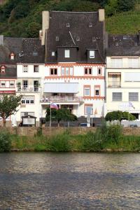 a large white building next to a body of water at Mosel View Old Town Apartments in Zell an der Mosel