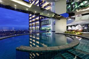 a hotel pool with a view of a city at night at The Gramercy Residences in Manila