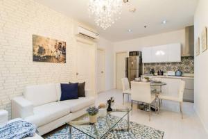 a living room with a white couch and a kitchen at The Gramercy Residences in Manila