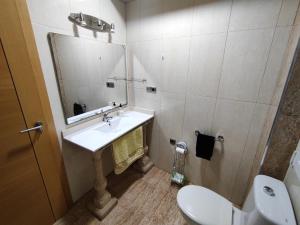 een badkamer met een wastafel, een toilet en een spiegel bij San Cristobal 2 in Orihuela
