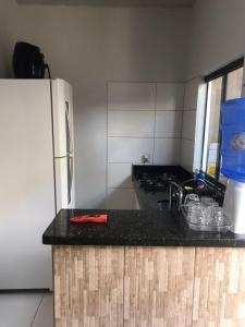 a kitchen with a black counter top and a white refrigerator at Studio Trivion- Px ao centro e praias in Palmas