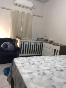 sypialnia z łóżkiem, krzesłem i łóżeczkiem dziecięcym w obiekcie Studio Trivion- Px ao centro e praias w mieście Palmas