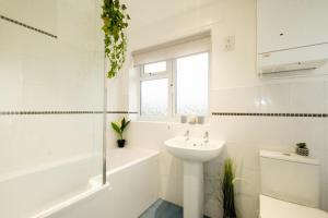 a white bathroom with a sink and a tub and a toilet at Hollybobs in Leiston