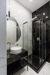 a bathroom with a glass shower and a sink at Villa Grey Hotel in Duliby