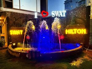 a water fountain in front of a building with lights at Swat Hilton Hotel by Khan Familia in Swat