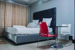 a bedroom with a bed with a red chair and a table at Stay Simple Lodge in Lusaka