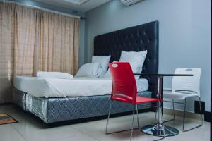 1 dormitorio con 1 cama con silla roja y mesa en Stay Simple Lodge, en Lusaka