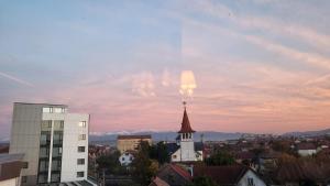 een kerktoren in een stad met een bewolkte hemel bij SIBIU Bach Penthouse in Sibiu