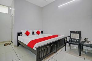 una camera da letto con un letto con cuscini rossi e una sedia di OYO Flagship Hornbill Residency a Alleppey
