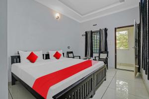 una camera da letto con un grande letto con cuscini rossi di OYO Flagship Hornbill Residency a Alleppey