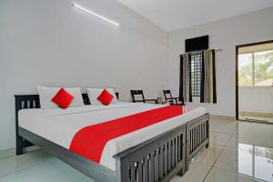 una camera da letto con un grande letto con cuscini rossi di OYO Flagship Hornbill Residency a Alleppey