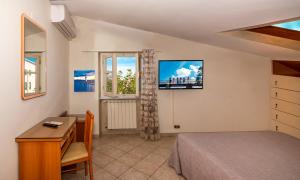 a bedroom with a bed and a desk and a television at Hotel Eura in Marina di Massa