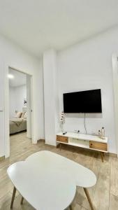 sala de estar blanca con mesa blanca y TV en Anna’s Home en Campanillas