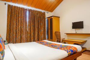 a bedroom with a bed and a desk and a television at FabHotel Lotus Resort in Aurangabad