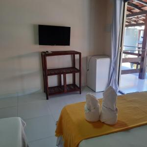 Habitación con cama, TV y mesa. en Ébano Pousada en Morro de São Paulo