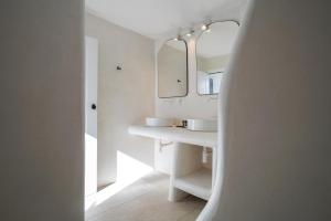 a white bathroom with two sinks and a mirror at 23 Hotel Mykonos in Mikonos